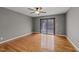 Spacious bedroom featuring hardwood floors, gray walls, a ceiling fan, and a sliding glass door to the backyard at 11404 Leesville Rd, Raleigh, NC 27613