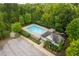 Aerial view of a community pool with a clubhouse, surrounded by lush greenery and ample parking at 120 Wellspring Dr, Holly Springs, NC 27540