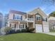 Two-story home boasting a welcoming balcony, stone accents, a two-car garage, and a lush green lawn at 120 Wellspring Dr, Holly Springs, NC 27540
