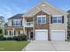 Charming two-story home featuring a stone facade, two-car garage, second story balcony, and landscaped front yard at 120 Wellspring Dr, Holly Springs, NC 27540