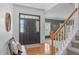 Bright foyer featuring hardwood floors, staircase, front door with sidelights, and a glimpse into the living room at 120 Wellspring Dr, Holly Springs, NC 27540
