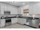 Modern kitchen with white cabinets, stainless steel appliances, black countertops, and bright lighting at 120 Wellspring Dr, Holly Springs, NC 27540