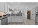 Open-concept kitchen showcasing white cabinets, black countertops, a stainless steel dishwasher, and open view to the living room at 120 Wellspring Dr, Holly Springs, NC 27540