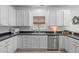 Well-lit kitchen with white cabinets, stainless steel appliances, dark countertops, and a window with a woven blind at 120 Wellspring Dr, Holly Springs, NC 27540