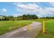 Scenic walking path with yellow bollards, surrounded by lush green grass and mature trees under a bright sky at 120 Wellspring Dr, Holly Springs, NC 27540