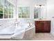 Bathroom featuring a soaking tub under corner windows with a wood vanity at 1204 Croydon Glen Ct, Cary, NC 27519