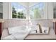 Bright bathroom featuring a soaking tub, corner windows, and neutral tiling at 1204 Croydon Glen Ct, Cary, NC 27519