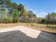 Backyard view of a concrete patio extending into green space and treeline at 1220 Falcon Ridge Ln, Morrisville, NC 27560