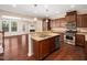 Gourmet kitchen featuring dark wood cabinets, granite countertops, stainless appliances, and an island with a sink at 1220 Falcon Ridge Ln, Morrisville, NC 27560