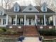 Inviting front porch with classic columns and brick accents that leads up to the main entrance at 1229 Westerham Dr, Wake Forest, NC 27587