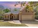 Charming home featuring mature trees, landscaping, and a two-car garage with an inviting front entry and warm facade at 1409 Turner Farms Rd, Garner, NC 27529