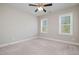 A carpeted bedroom with neutral walls, a ceiling fan, and two windows providing ample light at 142 Old Piedmont Cir, Chapel Hill, NC 27516