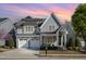 Charming two-story home featuring a two-car garage, gray siding, and manicured landscaping, solar panels, and a lovely sunset at 142 Old Piedmont Cir, Chapel Hill, NC 27516