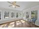 Bright sunroom featuring hardwood floors, ceiling fan, multiple windows with lakeside views, and comfortable seating at 155 Chimney Rise Dr, Cary, NC 27511