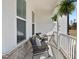 Inviting covered front porch featuring rocking chairs, throw pillows, brick accents, and hanging plants at 16 Blue Monarch Ln, Fuquay Varina, NC 27526