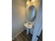 Powder room featuring a pedestal sink, oval mirror, and wood-look floors at 176 Bruce Dr, Dunn, NC 28334