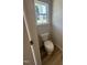 View of the toilet in the half bathroom with wood-look floors and a bright window at 176 Bruce Dr, Dunn, NC 28334