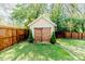 A backyard shed with natural wood doors is surrounded by a wooden fence and manicured lawn at 211 W Chisholm St, Sanford, NC 27330