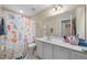 Bright bathroom with a patterned shower curtain, large mirror, and white vanity at 30 Holly Berry Ln, Durham, NC 27703