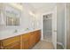 Well-lit bathroom with double vanity, framed mirrors, wood cabinets, and tile floor leading to bedroom at 304 Frontgate Dr, Cary, NC 27519