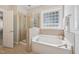 Elegant bathroom showcasing a soaking tub with tile surround and a glass-enclosed shower, all illuminated by natural light at 304 Frontgate Dr, Cary, NC 27519