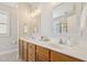 Bright bathroom featuring a double vanity with stone countertops, framed mirrors, and warm wood cabinetry at 304 Frontgate Dr, Cary, NC 27519