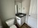 Well-lit powder room with granite countertop, white cabinet, toilet, mirror, and light wood-look flooring at 308 Busterfield Ct, Benson, NC 27504