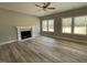 Cozy living room with a fireplace, ceiling fan, and abundant natural light from large windows at 308 Busterfield Ct, Benson, NC 27504