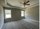 Spacious main bedroom with neutral carpet, tray ceiling, ceiling fan, and large windows, offering a serene retreat at 308 Busterfield Ct, Benson, NC 27504