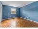 This bedroom features blue walls and hardwood flooring with a window for natural light at 3743 Yorktown Pl, Raleigh, NC 27609