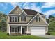 Charming two-story home featuring a two-car garage, stone accents, and a well-manicured lawn at 49 Olivia Crossing Ct # 43, Four Oaks, NC 27524