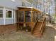 Inviting screened porch with wood frame, black railings, and stairs to access the backyard at 5120 Knaresborough Rd, Raleigh, NC 27612