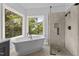 Modern bathroom with a freestanding tub and a glass shower, offering abundant natural light and scenic outdoor views at 6209 Remington Lake Dr, Raleigh, NC 27616