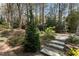 Lush backyard with mature trees, stone steps, and gravel paths, perfect for relaxing outdoors at 6719 Falconbridge Rd, Chapel Hill, NC 27517
