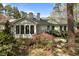 A backyard exterior with natural light, blooming landscaping, and plentiful windows at 6719 Falconbridge Rd, Chapel Hill, NC 27517