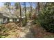 A backyard features a quaint gravel walking path with lush landscaping, trees and plantings at 6719 Falconbridge Rd, Chapel Hill, NC 27517