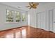 Bright bedroom featuring hardwood floors, ceiling fan, and abundant natural light through large windows at 6719 Falconbridge Rd, Chapel Hill, NC 27517