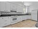 Well-lit kitchen featuring white cabinetry, tile backsplash, and modern appliances at 6719 Falconbridge Rd, Chapel Hill, NC 27517