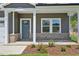 An inviting covered front porch featuring brick accents, a modern door, and manicured landscaping at 700 Deschutes Dr, Garner, NC 27529