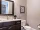 A bathroom features a dark vanity, toilet, mirror, and a marble countertop at 7312 Ridgeline Dr, Raleigh, NC 27613