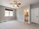 Neutral bedroom with carpet flooring, ceiling fan, window with wood blinds, and ensuite bathroom access at 7312 Ridgeline Dr, Raleigh, NC 27613