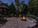 Beautiful stone fire pit with a seat wall and lighting, nestled in a lush backyard at 7312 Ridgeline Dr, Raleigh, NC 27613