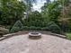 Charming stone fire pit surrounded by a curved seating wall and brick patio, nestled in a serene backyard at 7312 Ridgeline Dr, Raleigh, NC 27613