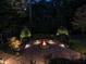 Nighttime view of stone fire pit with a seat wall and landscape lighting at 7312 Ridgeline Dr, Raleigh, NC 27613