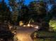 Backyard patio with a warm fire pit, complemented by landscape lighting and a tranquil atmosphere at twilight at 7312 Ridgeline Dr, Raleigh, NC 27613