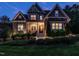 Charming two-story home with stone accents, manicured landscaping, and inviting front porch at dusk at 7312 Ridgeline Dr, Raleigh, NC 27613