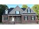 Traditional brick home featuring black shutters, a covered porch, and architectural roof elements at 801 Emmett Ct, Spring Hope, NC 27882