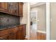 Hallway featuring wood floors, view to another room, and dark wood cabinets with black countertops at 915 Dunleigh Dr, Burlington, NC 27215