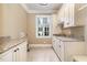 Laundry room features cream-colored cabinetry, granite countertops, tile flooring, and natural light at 915 Dunleigh Dr, Burlington, NC 27215