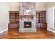 Cozy living room with stone fireplace, built-in shelving, and rich hardwood floors at 915 Dunleigh Dr, Burlington, NC 27215